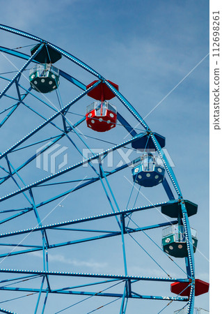 Colorful ride ferris wheel in motion in amusement park on sky background. Colorful ride ferris wheel in motion in amusement park on sky background. 112698261