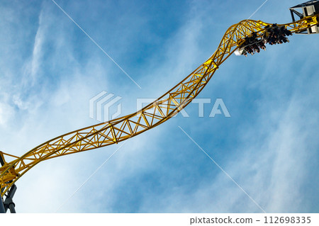 Ride roller coaster in motion in amusement park on blue sky background. 112698335