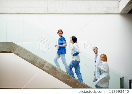 Portrait of team of doctors standing on stairs. Healthcare team with doctors, nurses, professionals in medical uniforms in hospital. Portrait of team of doctors standing on stairs. Healthcare team with doctors, nurses, professionals in medical uniforms in hospital. 112698440