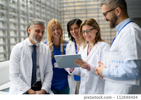 Group of doctors discussing test results, looking on tablet, medical team discussing patients diagnosis, searchign for right treatment. 112698484