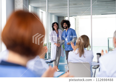 Female doctor as speaker at conference for healtcare workers, medical team sitting and listening presenter. Medical experts attending an education event, seminar in board room. 112698488