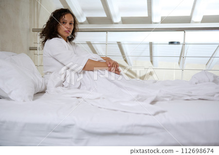 Young woman in bed, looking at camera, suffering from depression, mental health problem, insomnia, sleeping disorder, 112698674