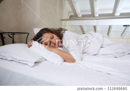 Stressed middle aged woman lying on bed at home and crying. Frustrated female feeling lonely Stressed middle aged woman lying on bed at home and crying. Frustrated female feeling lonely 112698680