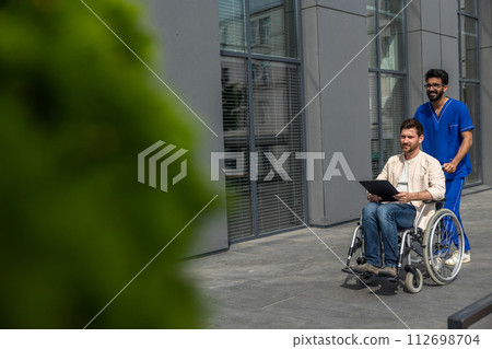 Disabled man having a walk with a male nurse and reading his prescription leaflet 112698704