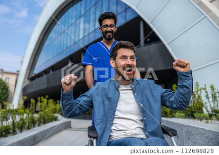 Young smiling bearded man in wheelchair having a walk with a nurse 112698828