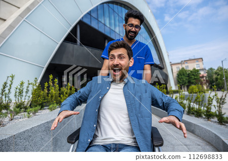 Young smiling bearded man in wheelchair having a walk with a nurse 112698833
