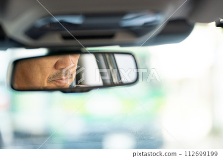Businessman driving a car rearview mirror Businessman driving a car rearview mirror 112699199