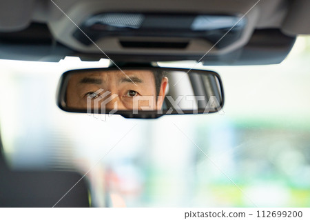Businessman driving a car rearview mirror Businessman driving a car rearview mirror 112699200