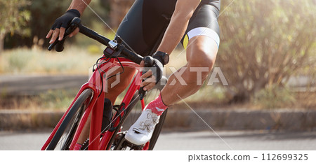 Road bike cyclist man cycling, athlete on a race cycle. Leaning into a corner Road bike cyclist man cycling, athlete on a race cycle. Leaning into a corner 112699325