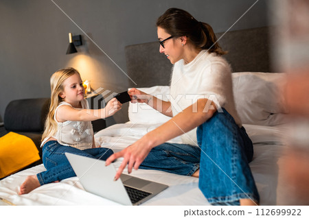 Little girl with mother doing shopping online using credit card and laptop for internet payment Little girl with mother doing shopping online using credit card and laptop for internet payment 112699922