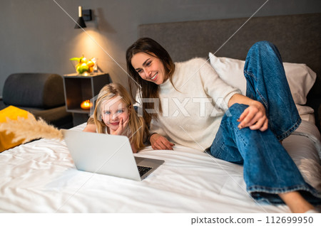 Little girl with mother having fun and using laptop for online entertainment during vacation 112699950