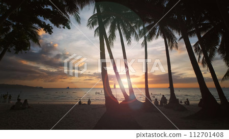 Sunset on beach with people and palms Sunset on beach with people and palms 112701408