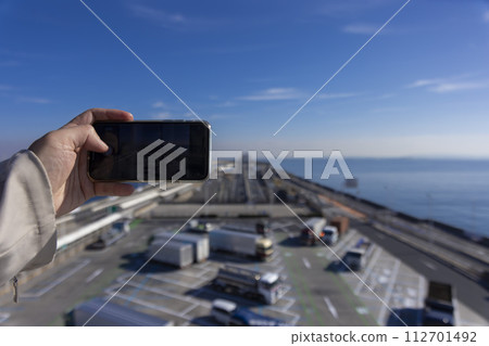People taking pictures of Umihotaru PA and Tokyo Bay Aqua Line with smartphones 112701492