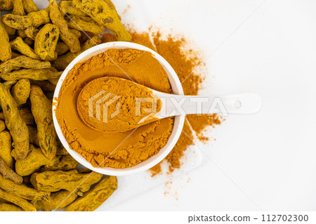 Turmeric powder, spices and dried root on white background. Top view, copy space for text. Turmeric powder, spices and dried root on white background. Top view, copy space for text. 112702300