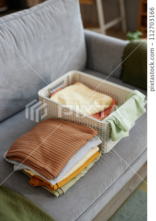 Vertical background image of clean clothes in stacks on couch in home interior Vertical background image of clean clothes in stacks on couch in home interior 112703166
