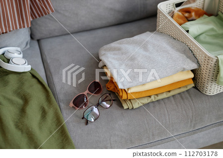 Background image of clean clothes in stacks ready for sorting and packing on sofa, copy space 112703178