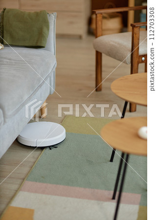 Vertical background image of white robot vacuum mopping floors under couch in cozy home copy space Vertical background image of white robot vacuum mopping floors under couch in cozy home copy space 112703308