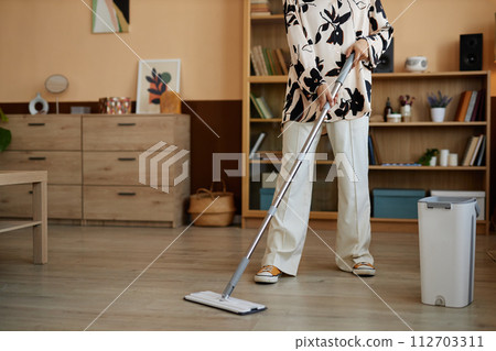 Cropped shot of young woman mopping floors in cozy home and wearing fun clothes copy space Cropped shot of young woman mopping floors in cozy home and wearing fun clothes copy space 112703311