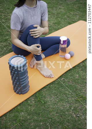 Feet of a woman wearing yoga wear stretching on the grass Feet of a woman wearing yoga wear stretching on the grass 112703447