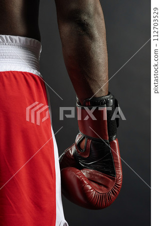 Vertical detail shot of male boxer wearing boxing glove on dark background Vertical detail shot of male boxer wearing boxing glove on dark background 112703529