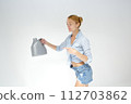 Smiling woman holding detergent bottle for machine wash. Isolated studio portrait on white. 112703862