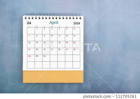 Directly above view of April 2024 desk calendar on blue wooden background. 112705261