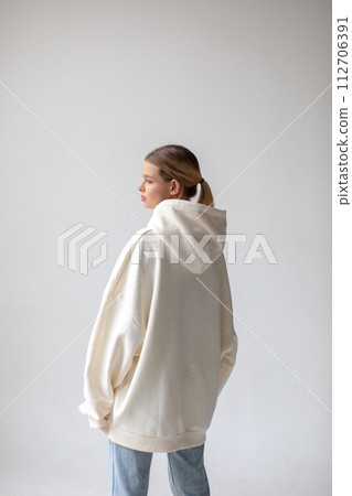 Beautiful blonde woman in a white hoodie and blue jeans posing on a white background 112706391