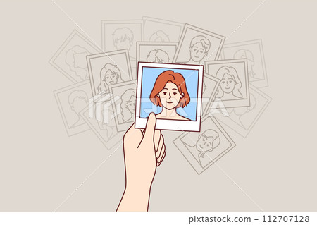 Photograph of woman in hands of human, looking at portraits of fellow students from college 112707128