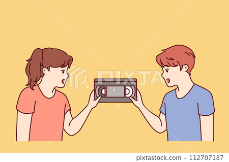 Surprised children are looking at film video cassette with movie recorded for VHS player Surprised children are looking at film video cassette with movie recorded for VHS player 112707187