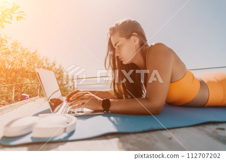 Woman laptop sea. Working remotely on seashore. Happy successful woman female freelancer working on laptop by the sea at sunset, makes a business transaction online. Freelance, remote work on vacation 112707202