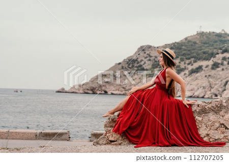 Woman travel portrait. Happy woman with long hair looking at camera and smiling. Close up portrait cute woman in a res long dress posing on backdrop of old travel city near sea Woman travel portrait. Happy woman with long hair looking at camera and smiling. Close up portrait cute woman in a res long dress posing on backdrop of old travel city near sea 112707205