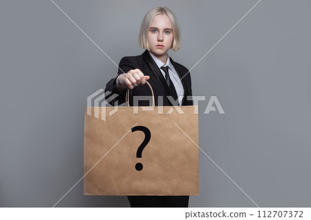 Pretty woman with shopping bag with question mark on grey background 112707372