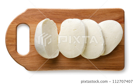 Mozzarella ball cut into pieces on a kitchen board on a white background. Top view Mozzarella ball cut into pieces on a kitchen board on a white background. Top view 112707407