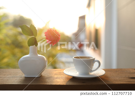 coffee cup and a white vase of rose flowers coffee cup and a white vase of rose flowers 112707710