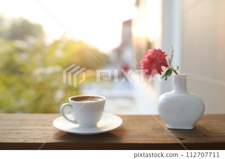 ceramic coffee cup and a white vase of rose flowers ceramic coffee cup and a white vase of rose flowers 112707711