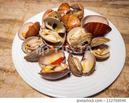 Fresh cooked opened venus clams with shells, served on a white dish top close-up view. 112708046