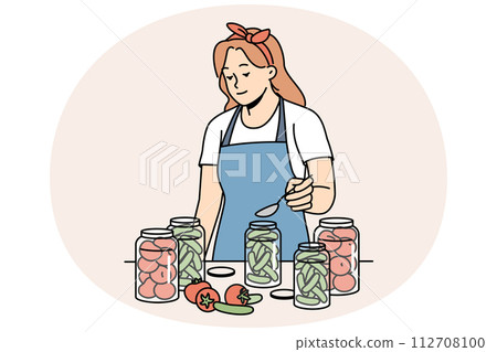 Woman in apron canning vegetables in bottles 112708100