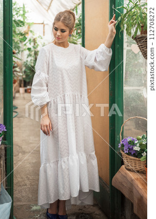 Young woman at a glass greenhouse Young woman at a glass greenhouse 112708272