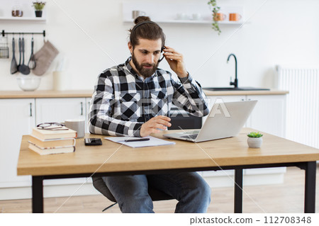 Businessman in headset gesture in front of computer while doing home-based job. Businessman in headset gesture in front of computer while doing home-based job. 112708348