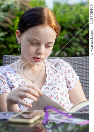 Young Redhead Woman Reading Book Outdoors 112708469
