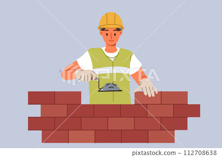 Man bricklayer builder builds brick wall using trowel with concrete mixture to secure blocks 112708638