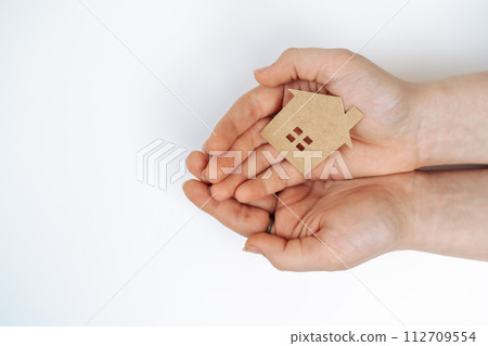 hands holding paper house, family home, homeless housing, mortgage crisis and home protecting insurance concept, foster home care, family day care, social distancing. hands holding paper house, family home, homeless housing, mortgage crisis and home protecting insurance concept, foster home care, family day care, social distancing. 112709554