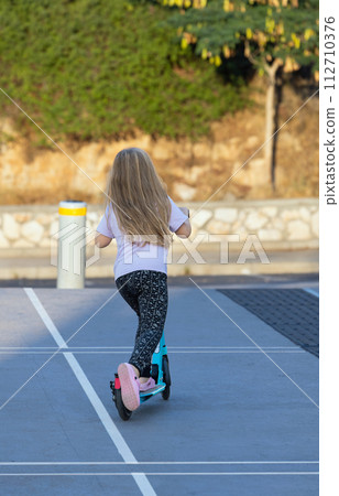 girl riding a scooter along 112710376