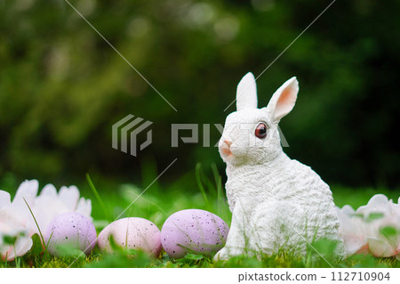 Easter background with bunny, eggs and flowers on green nature background with copy space 112710904