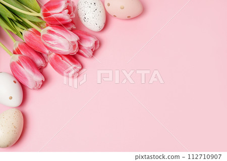 Colorful Easter eggs with pink bright tulips on pink background with copy space Colorful Easter eggs with pink bright tulips on pink background with copy space 112710907