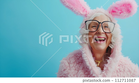 stylish Senior woman in Easter bunny costume smiling positive emotions blue background with place for text 112711087