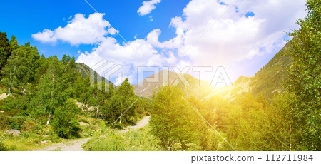 Picturesque mountains, meadow, bright sunrise and walking path. Wide photo. 112711984