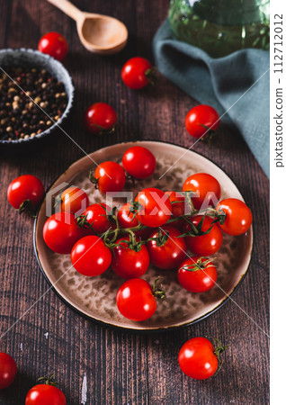 Plate with fresh cherry tomatoes on a wooden table vertical view Plate with fresh cherry tomatoes on a wooden table vertical view 112712012