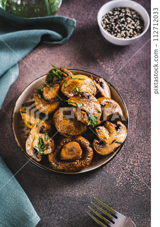 Homemade grilled mushrooms with herb on a plate on the table vertical view Homemade grilled mushrooms with herb on a plate on the table vertical view 112712033
