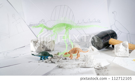 Children interest in dinosaurs and paleontology. A play area with drawings of Spinosaurus and its skeleton, an excavated Ankylosaurus skeleton, and a toy ankylosaurus model. Educational kid's hobby Children interest in dinosaurs and paleontology. A play area with drawings of Spinosaurus and its skeleton, an excavated Ankylosaurus skeleton, and a toy ankylosaurus model. Educational kid's hobby 112712105